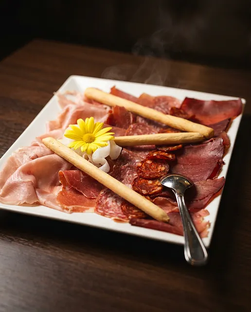 Antipasti-Platte mit Rohschinken, Bresaola und Grissini.