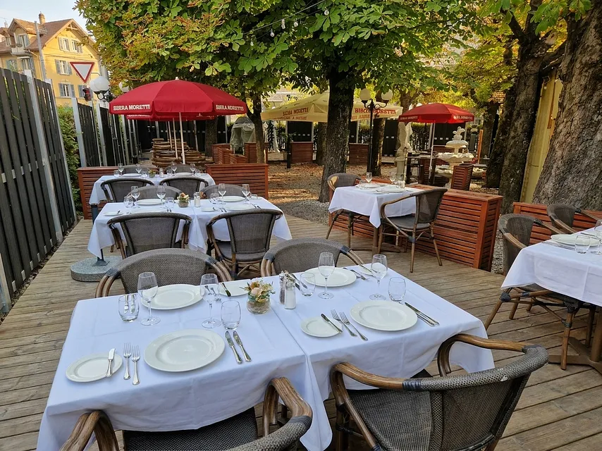 Gartenterrasse mit roten Schirmen im warmen Nachmittagslicht.